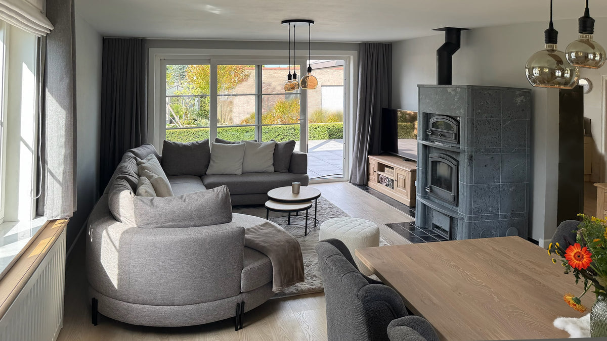 Geschwungenes graues Sofa neben dem Specksteinofen - Landhaus, Hamont