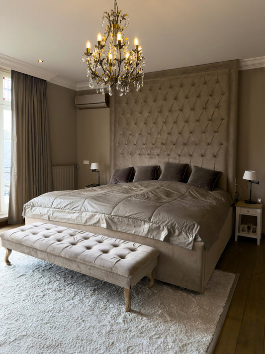 Restful bedroom with a tufted headboard, crystal chandelier and an upholstered bench