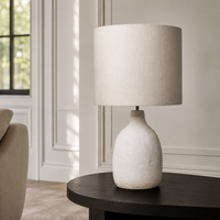 In-room lifestyle view of the Oskar 1916E table lamp placed on a console in a modern living room mit classic framing and velvet carpet, harmonised mit soft sunlight reflections. A 31 cm tall white 1xE27 table lamp for refined contemporary interiors, by Marcottestyle.