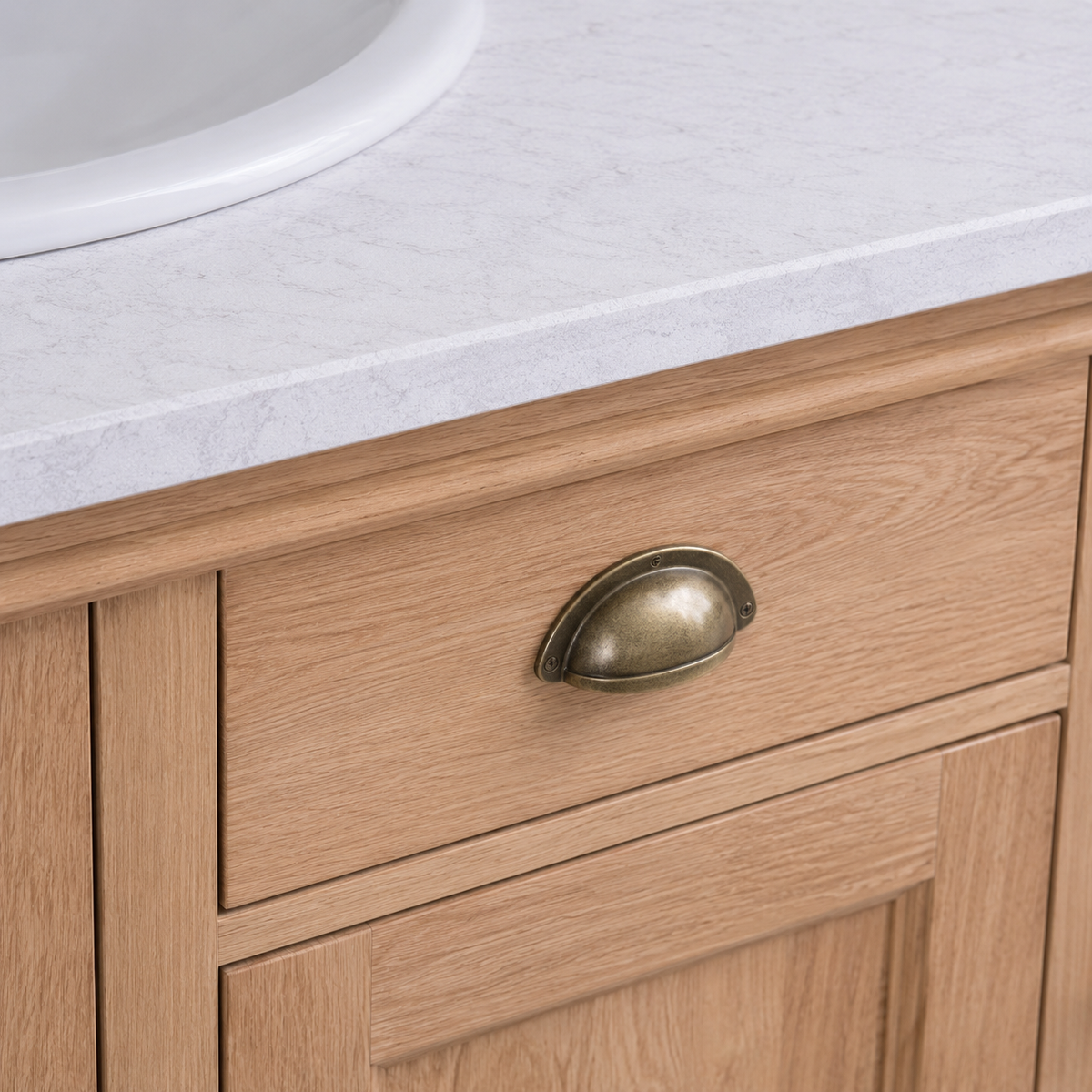 Antique brass cup handle on a natural oak drawer of the Arlington bathroom vanity, close-up