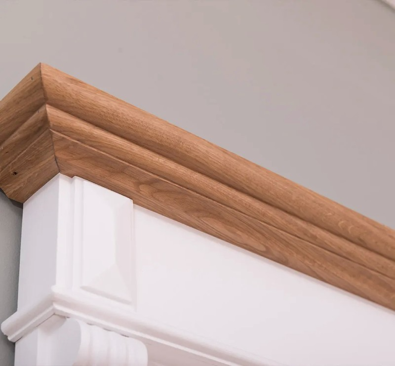 Close-up of the natural oak crown molding on top of the white Stratford Compact bathroom mirror