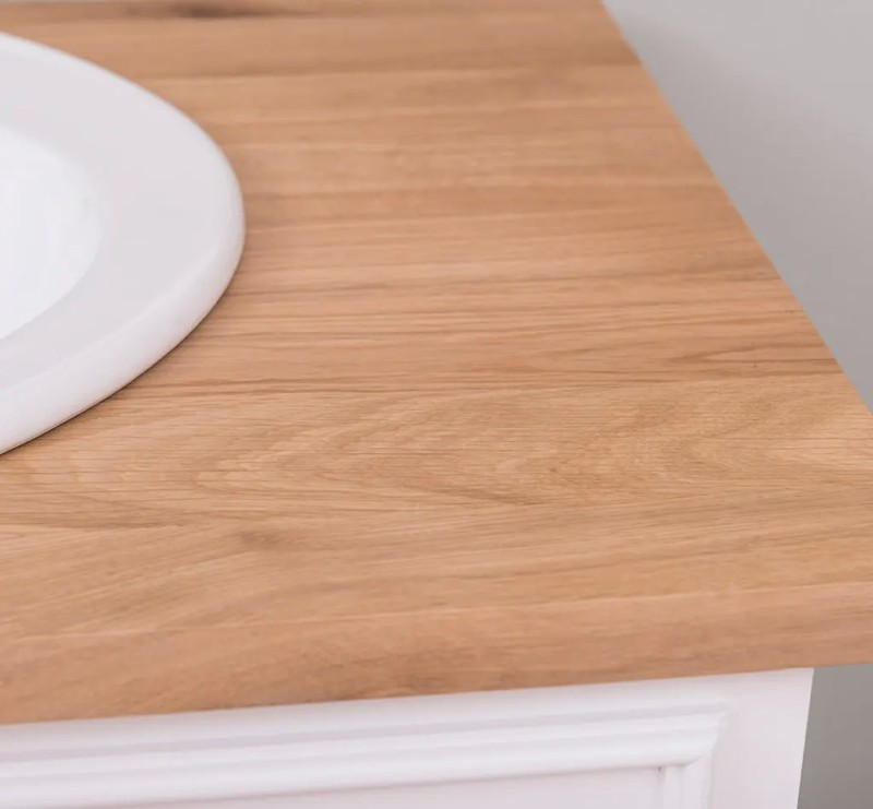 Close-up of the lacquered natural oak countertop corner beside the white sink, Stratford Compact vanity
