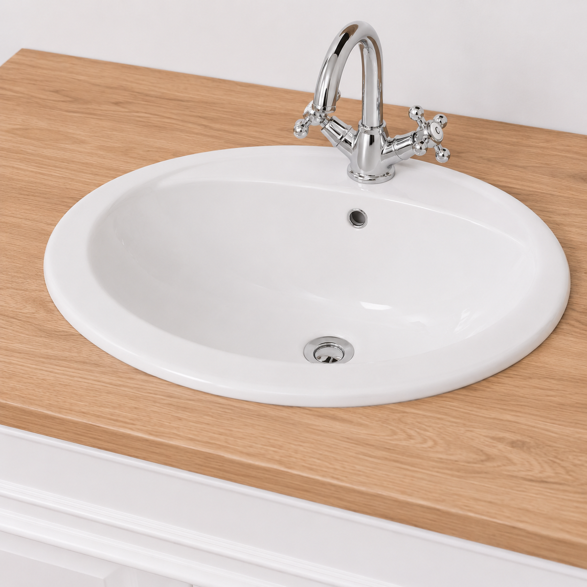 Close-up of the oval white sink and chrome cross-handle faucet on the oak Stratford Compact top