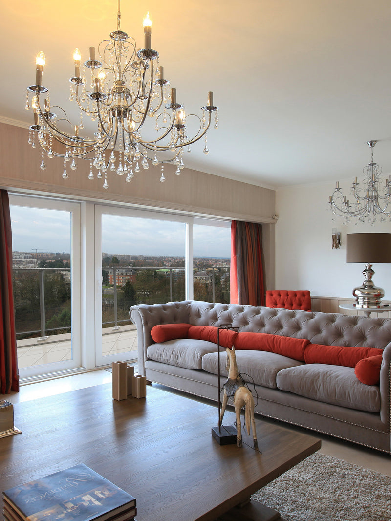Living room with gray sofa, red cushions, and a chandelier.