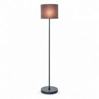 Floor Lamp Karin 6702B illuminated on white background — warm glow softly diffused through the black fabric shade, front view showing the lamp switched on by Marcottestyle